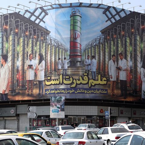 Iranians drive next to a billboard displaying pictures of nuclear scientists, centrifuges and a sentence reading in Farsi " Science is the power," at the Enqelab Square in Tehran, on Aug. 29, 2025. 
