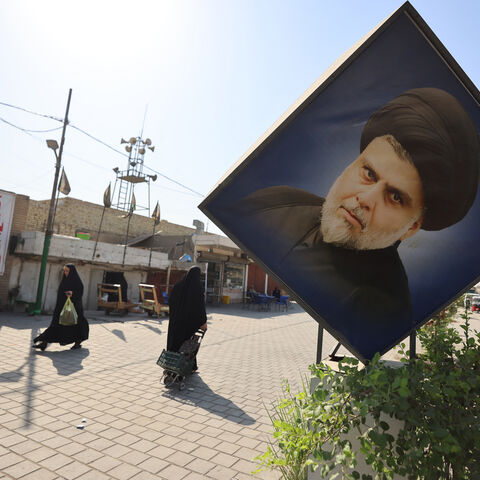Iraqis walk past portraits of Iraqi Shiite cleric Muqtada al-Sadr, including one on a banner calling for a boycott of the upcoming parliamentary elections in Sadr City, east of Baghdad on October 29, 2025. Parliamentary elections are scheduled to be held in Iraq on 11 November 2025, which will determine the 329 members of Iraq's Council of Representatives, who are responsible for electing the country's president and approving the appointment of the prime minister. (Photo by AHMAD AL-RUBAYE / AFP) (Photo by 