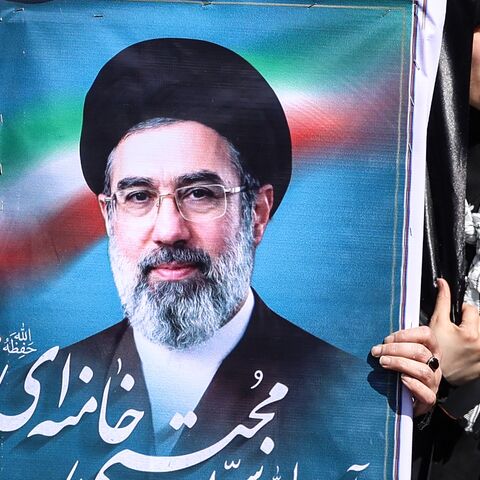 An Iranian woman holds up an image of Iran's new supreme leader Ayatollah Mojtaba Khamenei.