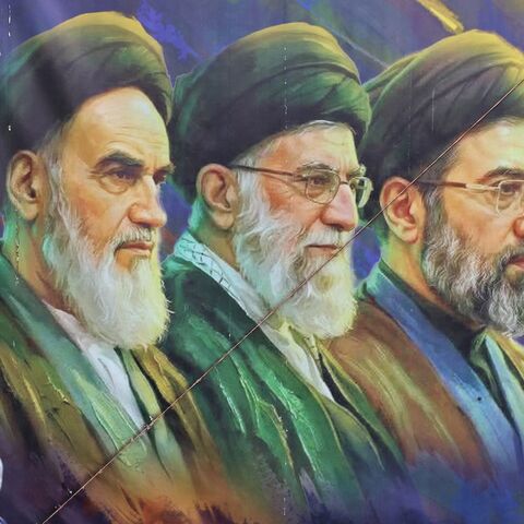 A woman walks past a banner featuring Iran's late supreme leaders, Ayatollah Ruhollah Khomeini (L) and Ayatollah Ali Khamenei (C), next to newly elected Supreme Leader Ayatollah Mojtaba Khamenei, in Tehran on April 19, 2026. 