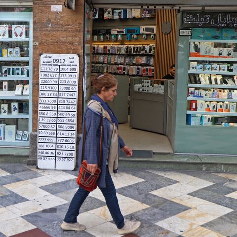 An Iranian woman walks past a mobile phone shop at the Valiasr Square in Tehran on April 19, 2026. 
