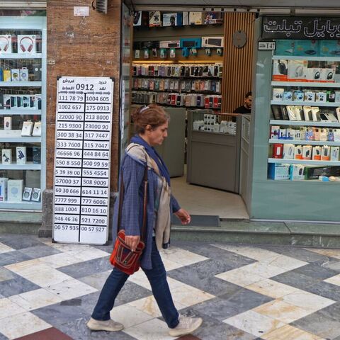 An Iranian woman walks past a mobile phone shop at the Valiasr Square in Tehran on April 19, 2026. — ATTA KENARE / AFP via Getty Images