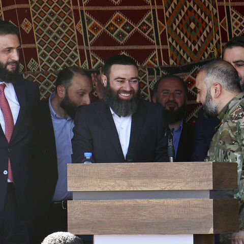 Syrian President Ahmed al-Sharaa (L) stands next to former Syrian rebel leader Issam Buwaydani (C), during a function in Douma on April 23, 2026. Buwaydani returned to Damascus on April 23 nearly a year after his detention for unknown reasons in the United Arab Emirates, a Syrian military official told AFP. (Photo by Bakr ALKASEM / AFP via Getty Images)