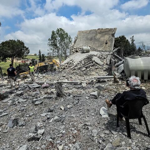 A man sits watching as Lebanese first responders search for human remains among the rubble the day after a house was targeted in an Israeli airstrike in the southern Lebanese city of Nabatieh, on May 1, 2026. 