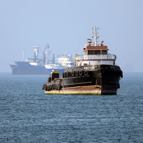 In this picture obtained from Iran's ISNA news agency on May 4, 2026, the Iran-flagged tugboat Basim sails near a ship anchored in the Strait of Hormuz off Bandar Abbas in southern Iran. 