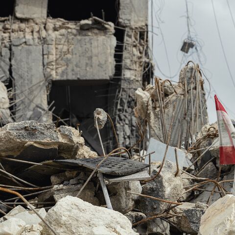 A view shows a Lebanese flag positioned among shattered concrete and twisted rebar, remnants of a destroyed building, in Sidon, Lebanon, on May 3, 2026. 