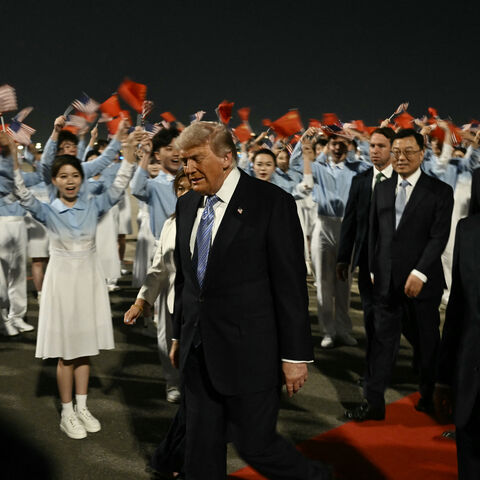TOPSHOT - US President Donald Trump (C) is escorted by China's Vice President Han Zheng (R) upon his arrival at Beijing Capital Airport in Beijing on May 13, 2026. (Photo by Brendan SMIALOWSKI / AFP via Getty Images)