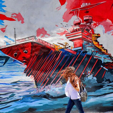A woman walks past an anti-US and anti-Israel mural depicting missiles hitting an aircraft carrier in Tehran on May 26, 2026.