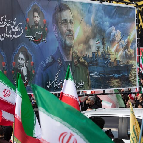 Members of the crowd wave Iranian flags during a funeral procession held for IRGC Navy Chief Alireza Tangsiri.