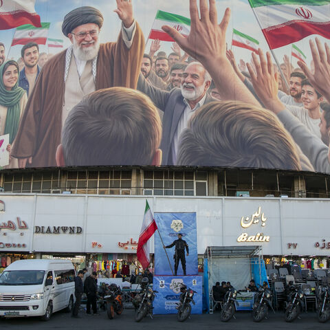 A police officer stands holding a flag in Valiasr Square beneath a mural of the late Ayatollah Ali Khamenei on April 23, 2026 in Tehran, Iran. 