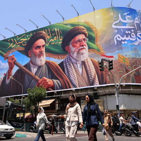 TOPSHOT - People cross the street past a large billboard showing portraits of Iran's late supreme leader, Ayatollah Ruhollah Khomeini (L) and slain supreme leader Ayatollah Ali Khamenei (R) in central Tehran on June 8, 2026. Iran said on June 8 that the resumption of hostilities in the Middle East war will have consequences for ongoing talks with the United States to reach peace in the region. "It is perfectly natural that the diplomatic process initiated to put an end to this imposed war would be affected,