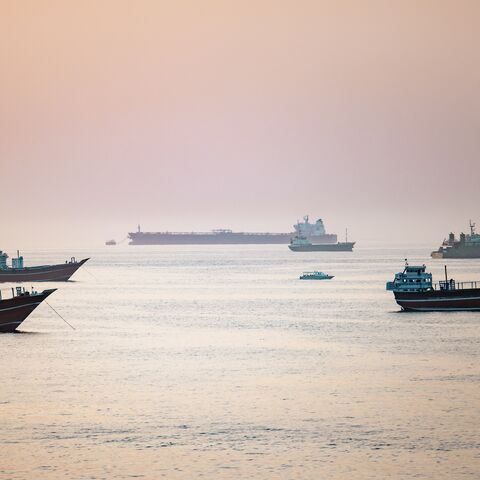 A tourist boat passes near crude oil tankers, bulk carriers, and other vessels anchored off Port Sultan Qaboos in Muscat, Oman, June 19, 2026. 
