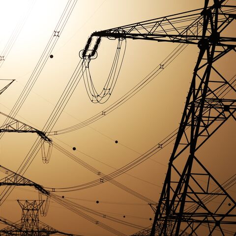 The sun sets behind overhead power lines in Kuwait City, June 19, 2024.