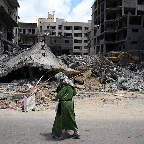A woman walks past flattened building as workers remove the rubble from the site of an earlier Israeli military strike on a neighbourhood in the southern Lebanese coastal city of Tyre on June 23, 2026. On June 22, 2026, mediators Pakistan and Qatar said that Tehran and Washington had agreed to set up a "de-confliction cell" to limit flare-ups in Lebanon following talks in Switzerland on ending the wider Middle East war, which Tehran has linked to halting the parallel conflict in Lebanon. (Photo by Joseph EI