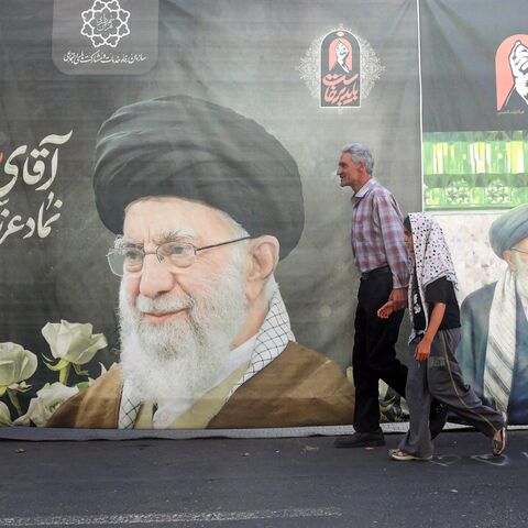 Iranians walk past a billboard bearing a picture of Iran's slain supreme leader Ali Khamenei ahead of his funeral in Tehran on July 3, 2026. Iranian leaders began paying their respects on July 3 before the coffin of the country's late supreme leader Ali Khamenei, killed in the US-Israeli strikes that triggered the Middle East war, as Tehran prepared for a vast funeral. Khamenei's body arrived at Tehran's Grand Mosalla on July 3 ahead of ceremonies which are expected to draw millions. (Photo by AFP via Getty
