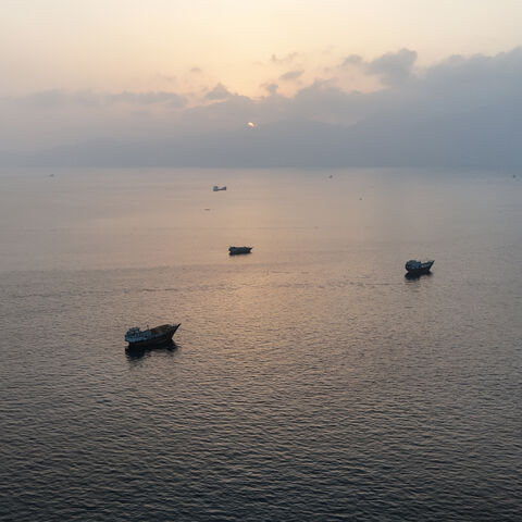 TOPSHOT - This aerial photograph shows boats anchored off Oman's northern Musandam Peninsula near the Strait of Hormuz on June 27, 2026. Iran launched attacks on US sites in the Gulf in response to American strikes on the country, state media said on June 27, after Washington accused Tehran of attacking one of its cargo ships in the Strait of Hormuz. The trading of fire raised questions about efforts to keep the crucial waterway open while Washington and Tehran negotiate a final settlement to a war that beg