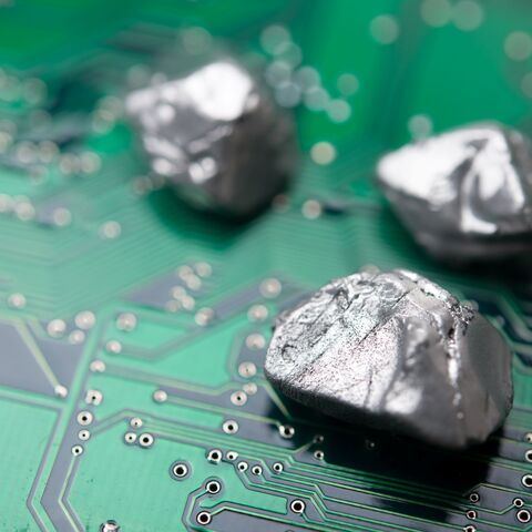 Rare earth mineral on a green electronic circuit board. — Getty Images stock photo