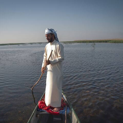 A man uses a pole to navigate a boat