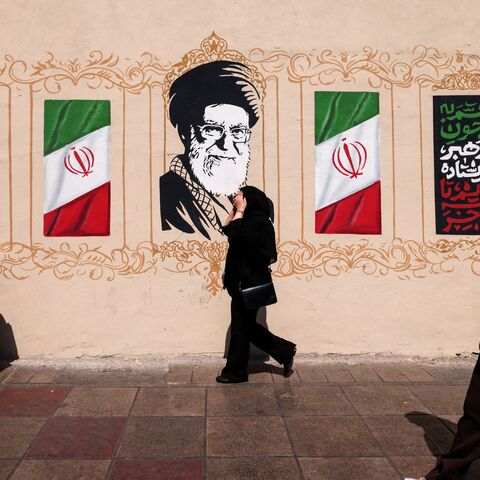 Iranians walk past a wall decorated with the image of assassinated Iranian supreme leader Ayatollah Ali Khamenei and the national flag, in central of Tehran on Sept. 14, 2026.  