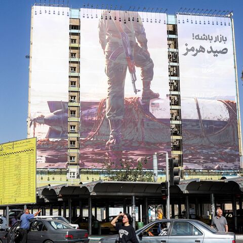 A woman crosses a street near a giant billboard erected on the facade of a building depicting a member of Iran's Islamic Revolutionary Guards Corps placing his foot on a US sea drone, reportedly seized by Iran in the Strait of Hormuz, in Vanak Square in Tehran, on Sept. 24, 2026.