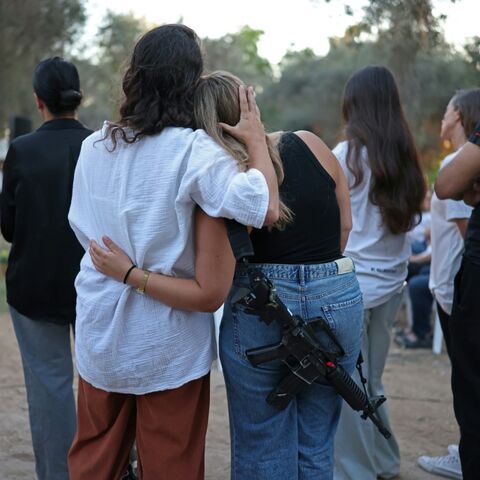 Israelis embrace one another while attending an October 7 attack three-year-anniversary tribute ceremony at the Kibbutz Kfar Aza
