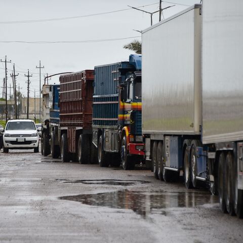 Trucks loaded with goods wait to cross over to Syria