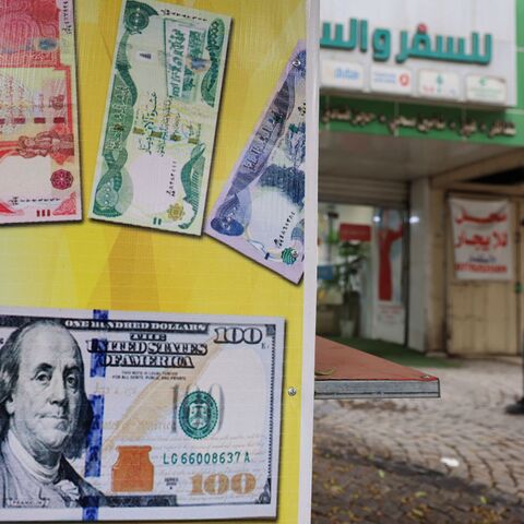 A man walks past a closed foreign exchange office in Baghdad on October 7, 2026. Iraq's central bank devalued the dinar currency against the dollar on October 7, with the country facing a deepening crisis brought on by the Middle East war. (Photo by AHMAD AL-RUBAYE / AFP via Getty Images)
