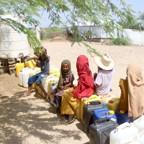 Internally displaced Yemenis queue at a water tank dispenser