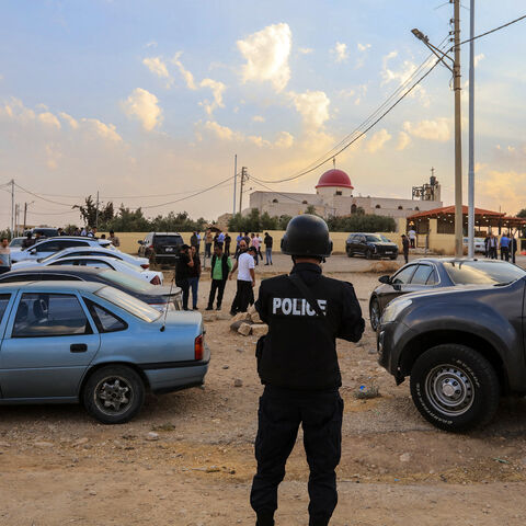 People and security forces gather outside a Greek Orthodox Church in the village of Hammoud in Jordan's Karak governorate following a shooting on October 23, 2026. 