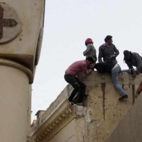 Coptic Christians run on the roof of the main cathedral in Cairo as police fire tear gas during clashes with Muslims standing outside the cathedral April 7, 2013. Clashes broke out between Coptic Christians and Muslims in central Cairo on Sunday after the funeral of four Copts killed in sectarian violence outside the Egyptian capital on Friday night, witnesses said.  REUTERS/Asmaa Waguih (EGYPT  - Tags: RELIGION CIVIL UNREST) - RTXYC7G
