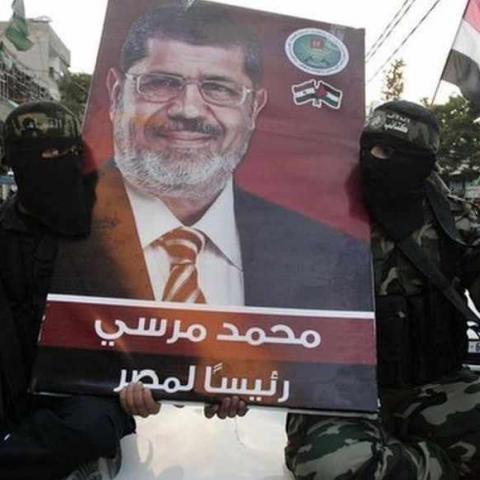 Hamas militants hold a poster depicting Mohamed Morsy of the Muslim Brotherhood as they celebrate in the street in Gaza City after he was declared Egypt's first democratic president June 24, 2012. Morsy's win was hailed by Hamas, the Islamist group governing Gaza and which is locked in a power-struggle with the West Bank-based, U.S.-backed Palestinian Authority of President Mahmoud Abbas. REUTERS/Mohammed Salem (GAZA - Tags: POLITICS ELECTIONS TPX IMAGES OF THE DAY MILITARY) - RTR343IV