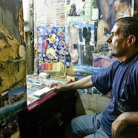 An Iraqi man sells tickets at the Atlas Cinema in the Iraqi city of Basra on May 27, 2003. Basra's cinemas closed this month after threats from radical Muslims but reopened on Tuesday, although they are showing only action and Arabic films and not the more popular "romance" movies. - RTXLZXN