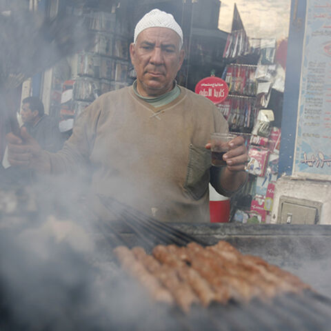 A man grills kebab, which is used to prepare sandwiches for passers-by, along a street corner in Cairo February 23, 2010. REUTERS/Asmaa Waguih(EGYPT - Tags: FOOD SOCIETY) - RTR2AROO