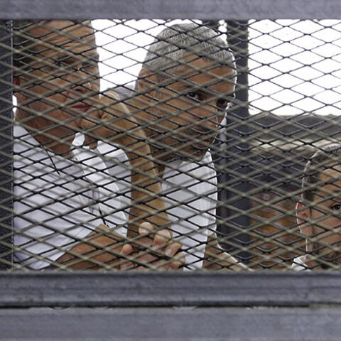 Al Jazeera journalists (L-R) Peter Greste, Mohammed Fahmy and Baher Mohamed stand behind bars at a court in Cairo June 1, 2014. The trial of the three Al Jazeera journalists accused of aiding of a "terrorist organisation" has been postponed to June 6. The Qatar-based television network's journalists - Peter Greste, an Australian, Mohamed Fahmy, a Canadian-Egyptian national, and Baher Mohamed, an Egyptian - were detained in Cairo on December 29. All three have denied the charges, with Al Jazeera saying the a