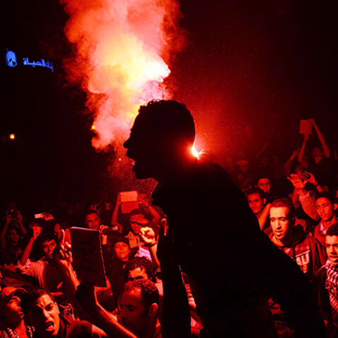 Egyptian protesters use flare lights at Talaat Harb Square in downtown Cairo on November 26, 2013 during a clash with police after the security forces dispersed protesters from a demonstration organized by human rights group "No Military Trials for Civilians" in the first unauthorised protest staged in the capital since the adoption of a law that regulates demonstrations. Egypt's interim president Adly Mansour passed a law that allows security forces to gradually step up force while dispersing protestors. A