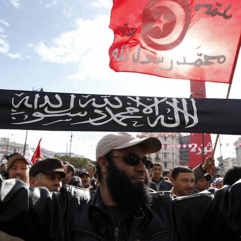 A man from the Salafist faction holds up a banner that reads "There is no god but God, and Muhammad is the messenger of God", on the second anniversary of the Tunisian Revolution at Avenue Habib Bourguiba in Tunis January 14, 2013. Thousands of Tunisians protested against the Islamist-led government on Monday, exactly two years after the overthrow of President Zine El Abidine Ben Ali in a popular revolt that inspired others across the Arab world. In the same street, about 2,000 supporters of the Islamic-led