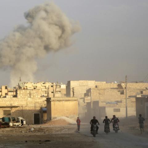 Men ride motorcycles as smoke rises because of, what activists said was, an airstrike carried out by the Russian air force in the rebel-controlled area of Maaret al-Numan town in Idlib province, Syria October 24, 2015. REUTERS/Khalil Ashawi - RTS7RYZ