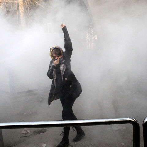 TOPSHOT - An Iranian woman raises her fist amid the smoke of tear gas at the University of Tehran during a protest driven by anger over economic problems, in the capital Tehran on December 30, 2017.
Students protested in a third day of demonstrations sparked by anger over Iran's economic problems, videos on social media showed, but were outnumbered by counter-demonstrators. / AFP PHOTO / STR        (Photo credit should read STR/AFP/Getty Images)