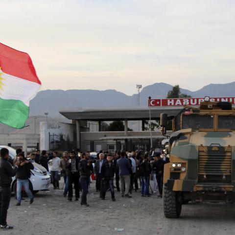 A man waves a Kurdistan flag as a Turkish military truck escorts a convoy of peshmerga vehicles at Habur border gate, which separates Turkey from Iraq, near the town of Silopi in southeastern Turkey, October 29, 2014. Iraqi peshmerga fighters arrived in southeastern Turkey early on Wednesday ahead of their planned deployment to the Syrian town of Kobani to help fellow Kurds repel an Islamic State advance, a Reuters witness said. REUTERS/Kadir Baris (TURKEY - Tags: POLITICS MILITARY CONFLICT TPX IMAGES OF TH