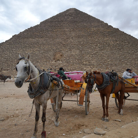 This picture taken on December 29, 2018 shows tourist horse-drawn carts waiting by the base of the Great Pyramid of Khufu (or Cheops) at the Giza necropolis on the southwestern outskirts of the Egyptian capital Cairo on December 29, 2018. (Photo by MOHAMED EL-SHAHED / AFP)        (Photo credit should read MOHAMED EL-SHAHED/AFP/Getty Images)