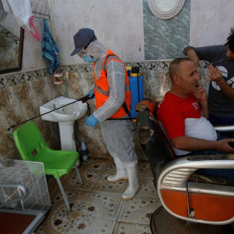 A worker in protective suit sprays disinfectants in a barber shop at popular market, following an outbreak of the coronavirus, in Basra, Iraq March 10, 2020. REUTERS/Essam al-Sudani - RC24HF95V7S1