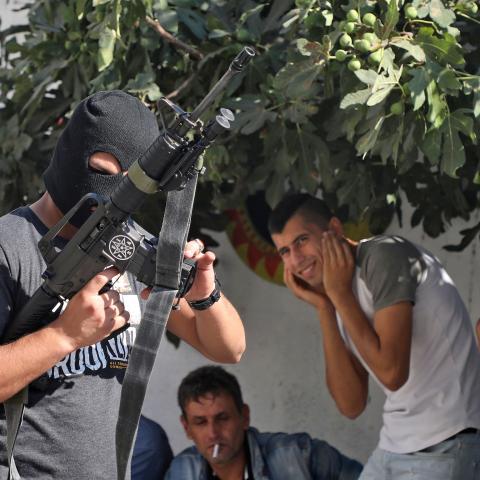 Palestinians cover their ears as a masked man fires a volley from his rifle, during the funeral of Dalia Ahmed Suleiman Samudi, 23, in Jenin city in the occupied West Bank on August 7, 2020, who was killed by Israeli fire during clashes. - Samudi died of a gunshot wound after being shot near the site of clashes between Palestinian youths and Israeli troops in the occupied West Bank, Palestinian officials said. (Photo by JAAFAR ASHTIYEH / AFP) (Photo by JAAFAR ASHTIYEH/AFP via Getty Images)