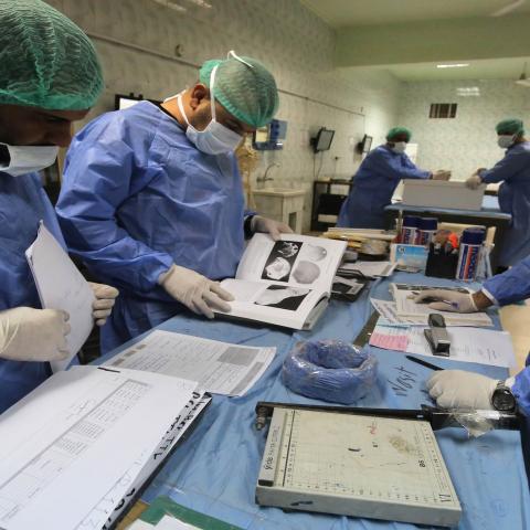 Staff at Iraqi forensics lab Medico-Legal Directorate in eastern Baghdad inspect samples on June 19, 2019. - The bones, recently exhumed from mass graves in the Yazidi stronghold of Sinjar in northwest Iraq, will be compared with blood samples from surviving members of the community to help determine the fates of those still missing after the Islamic State group's 2014 sweep across their villages. Entire families were massacred, boys recruited to fight and women and girls forced into "sex slavery" in what t