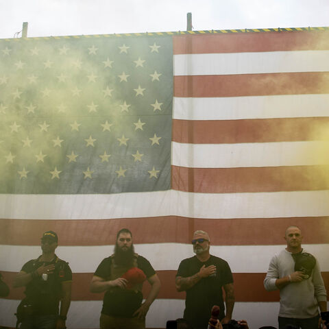 Yellow smoke fills the air as an American flag is raised at the start of a Proud Boys rally at Delta Park in Portland, Oregon on September 26, 2020. - Far-right group "Proud Boys" members gather in Portland to show support to US president Donald Trump and to condemn violence that have been occurring for more than three months during "Black Lives Matter" and "Antifa" protests. (Photo by Maranie R. STAAB / AFP) (Photo by MARANIE R. STAAB/AFP via Getty Images)