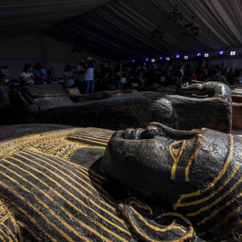 A picture taken on October 3, 2020 shows sarcophaguses, excavated by the Egyptian archaeological mission which discovered a deep burial well with more than 59 human coffins closed for more than 2,500 years, displayed during a press conference  at the Saqqara necropolis, 30 kms south of the Egyptian capital Cairo. - They were unearthed south of Cairo in the sprawling burial ground of Saqqara, the necropolis of the ancient Egyptian capital of Memphis, a UNESCO World Heritage site. Their exteriors are covered 