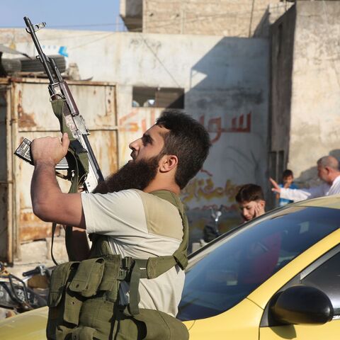 A fighter with the Turkey-backed Faylaq al-Sham rebel faction in Syria shoots in the air during the funeral of 10 of the faction's fighters in the northwestern city of Idlib, on October 26, 2020, following their death in a Russian air strike. - Air strikes by Syrian regime ally Russia killed 78 fighters from the turkey-backed Faylaq al-Sham faction when they targeted a training camp in the Jabal Duwayli area in Idlib province, the Syrian Observatory for Human Rights said. (Photo by Mohammed AL-RIFAI / AFP) 