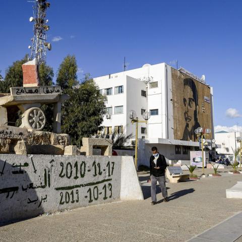 A man walks past a sculpture of Mohamed Bouazizi's cart (bearing text reading in Arabic: "I do not forgive") in the square named after him in the centre of the town of Sidi Bouzid in central Tunisia on October 27, 2020, the cradle of the 2011 Tunisian revolution where unemployment remains high ten years later. - The sister of Mohamed Bouazizi, whose self-immolation sparked a string of Arab uprisings, says she is "very disappointed" in Tunisia's revolution and has urged young Tunisians to continue the fight 