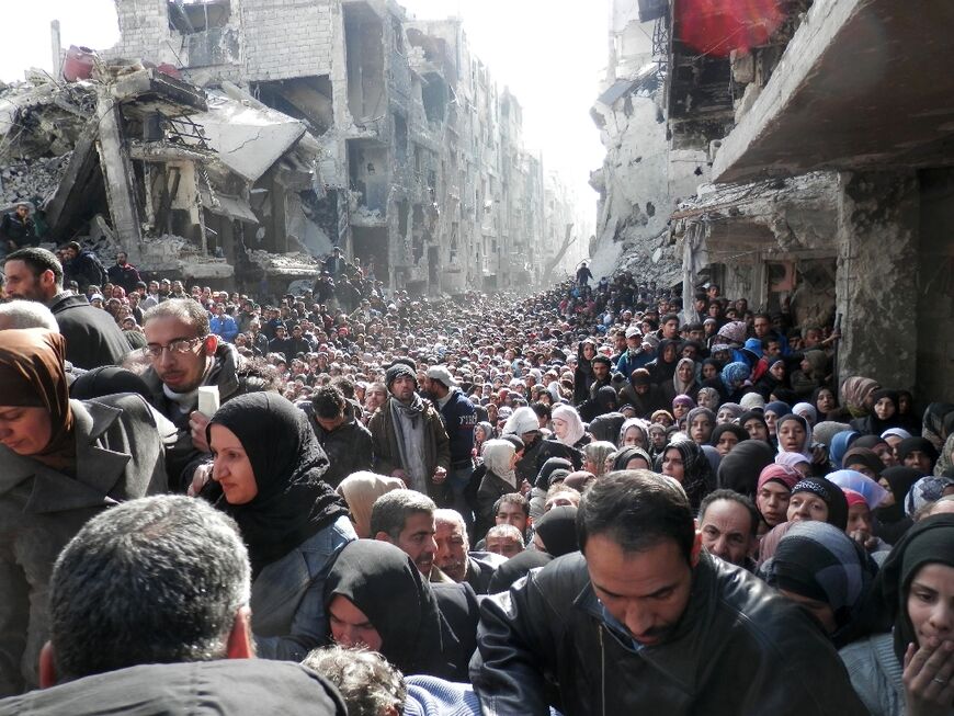 Residents wait for food at a UN distribution point in the Yarmuk refugee camp south of Damascus in 2014