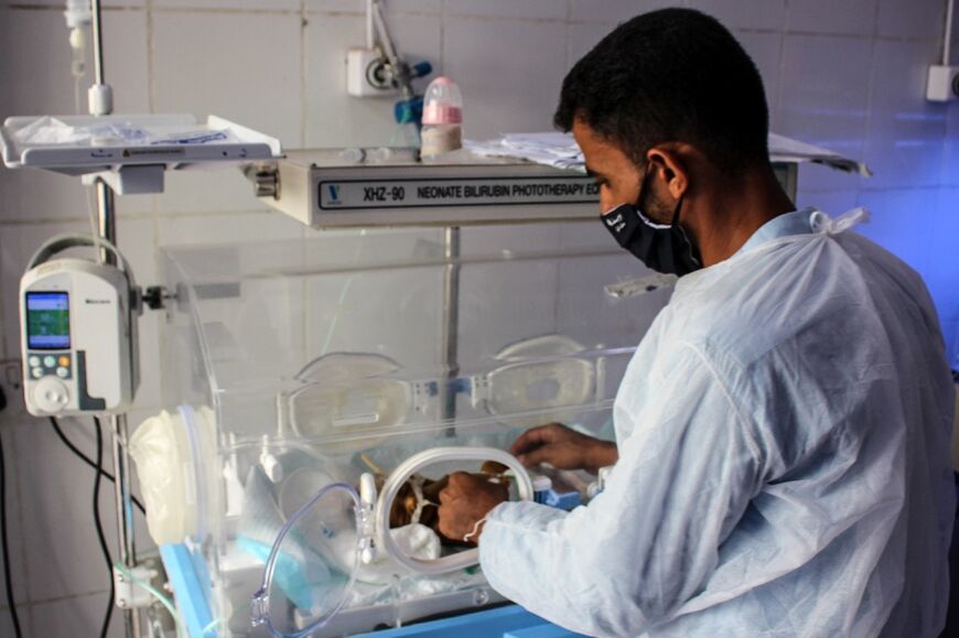 A doctor checks on a premature newborn in an incubator at Al-Sadaqa hospital