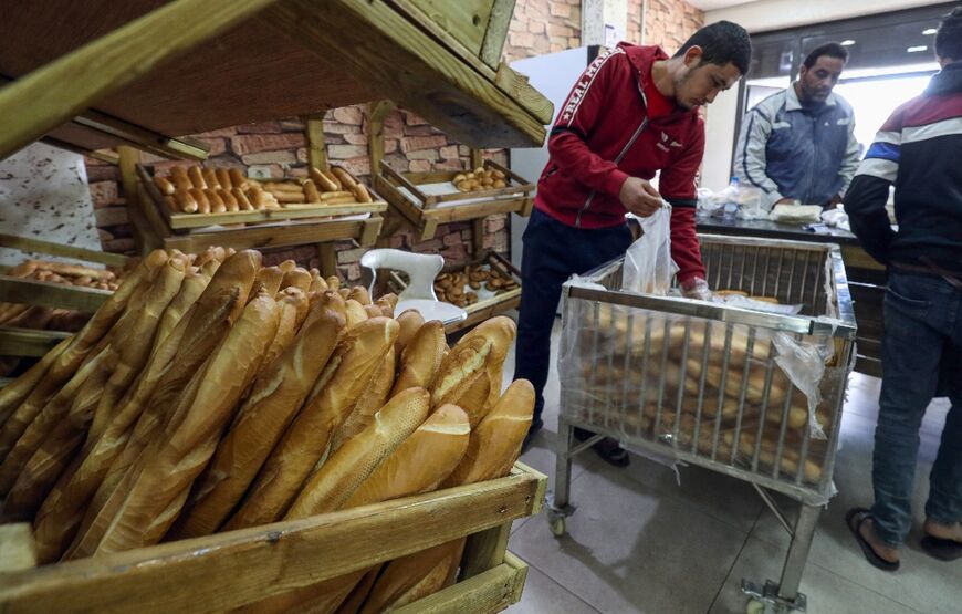 Libyan employees sell bread at a bakery in the capital Tripoli
